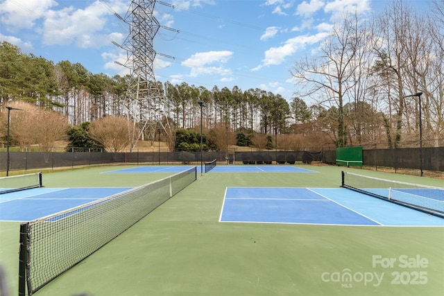 view of tennis court featuring community basketball court and fence