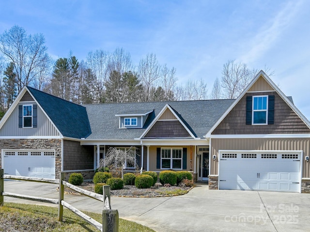 craftsman-style home featuring a garage, a shingled roof, concrete driveway, stone siding, and board and batten siding