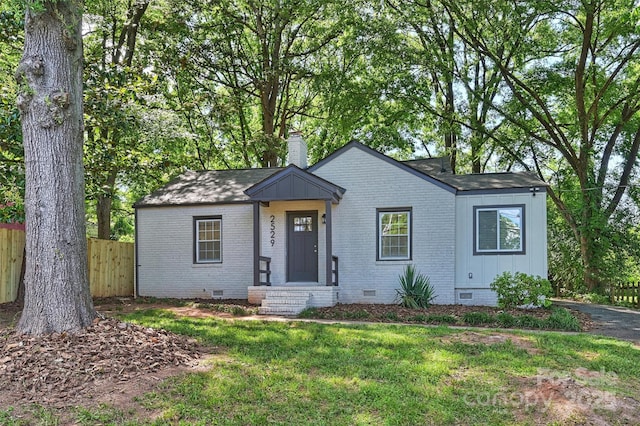 view of front of home with crawl space, brick siding, fence, and a chimney