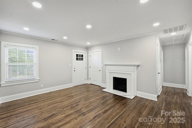 unfurnished living room featuring a fireplace with raised hearth, wood finished floors, visible vents, attic access, and crown molding