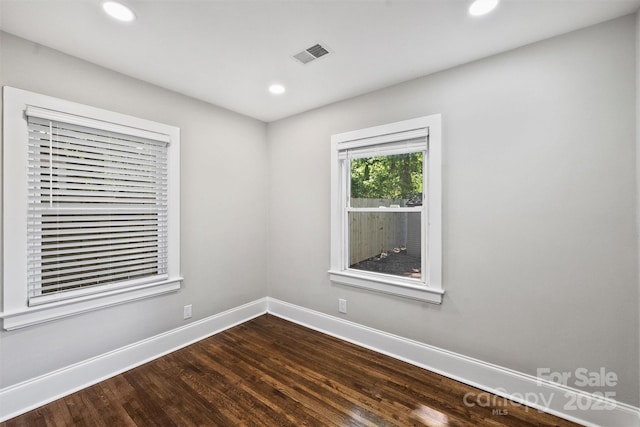 empty room with dark wood-type flooring, recessed lighting, visible vents, and baseboards