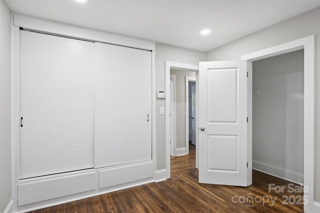 unfurnished bedroom with dark wood-style floors, a closet, recessed lighting, and baseboards