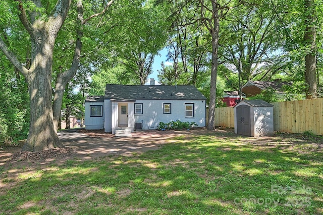 exterior space with a chimney, an outbuilding, fence, a storage unit, and a front yard