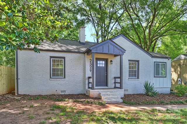 bungalow-style home featuring brick siding, fence, crawl space, board and batten siding, and a chimney