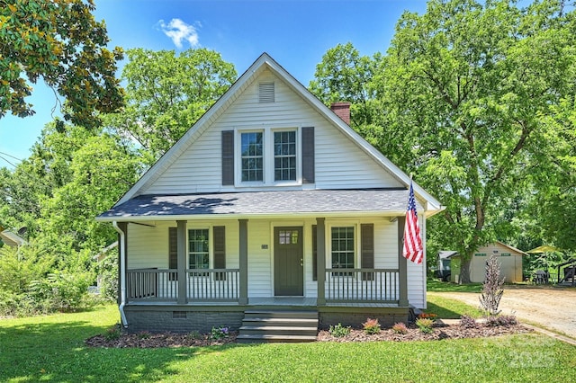 bungalow featuring a porch, a chimney, a front yard, and a shingled roof