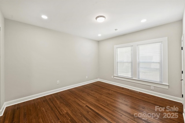 unfurnished room with recessed lighting, dark wood finished floors, visible vents, and baseboards