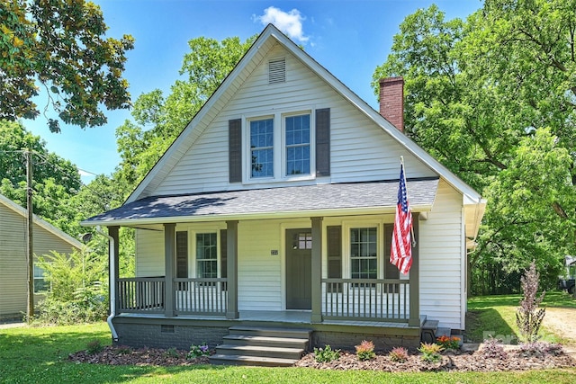 bungalow featuring covered porch, a shingled roof, a chimney, and a front lawn