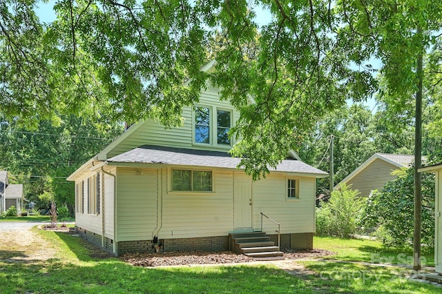 rear view of house featuring entry steps, crawl space, roof with shingles, and a yard