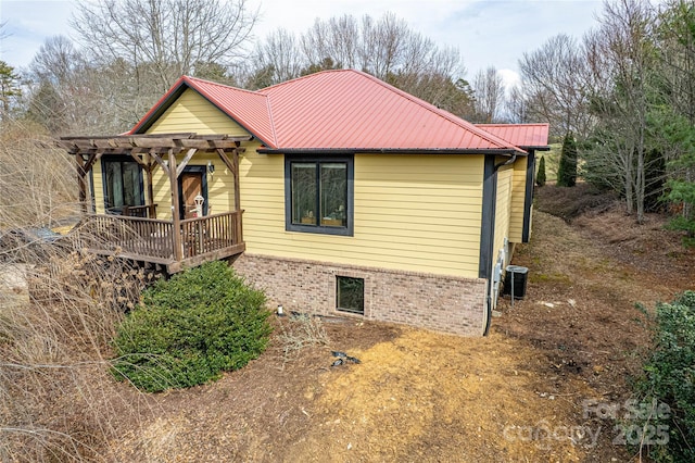 view of front of home featuring a deck, metal roof, a pergola, and brick siding