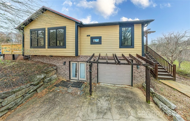 back of property with a garage, french doors, brick siding, and driveway