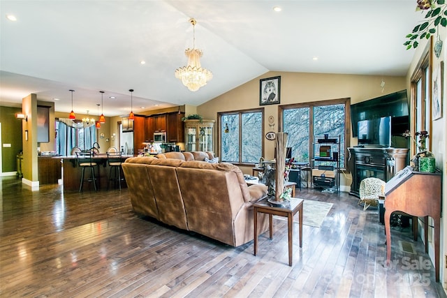 living area featuring a chandelier, dark wood-type flooring, vaulted ceiling, and baseboards