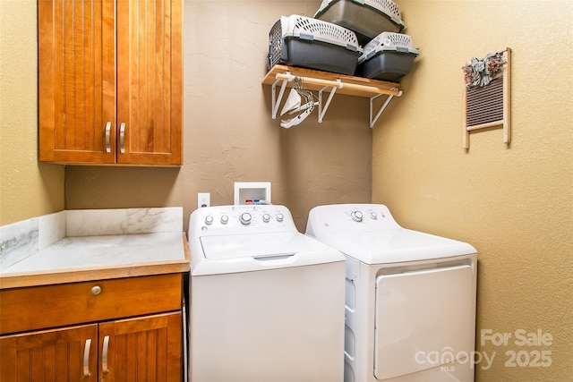 washroom featuring cabinet space, washing machine and dryer, and a textured wall