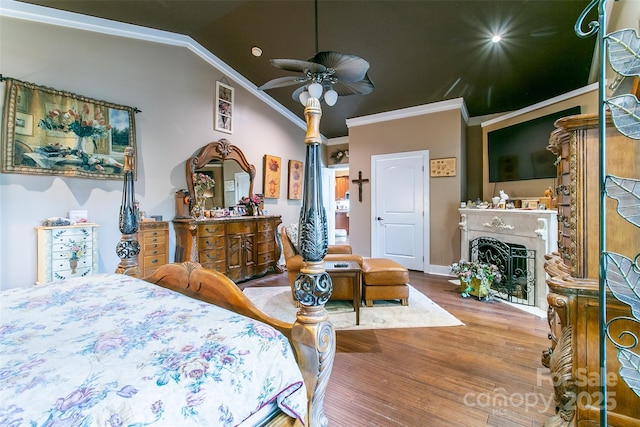 bedroom featuring ornamental molding, a fireplace, vaulted ceiling, and wood finished floors