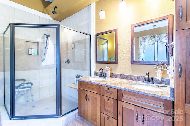 full bath featuring double vanity, a stall shower, and a sink