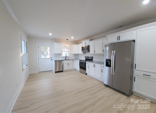 kitchen with decorative backsplash, light wood-style flooring, stainless steel appliances, white cabinetry, and a sink