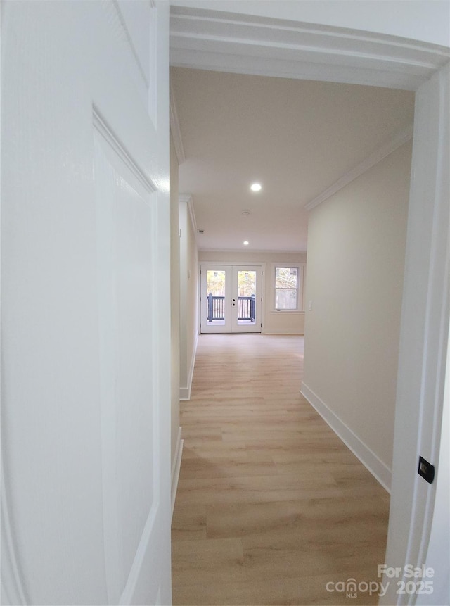 hallway featuring baseboards, crown molding, french doors, light wood-type flooring, and recessed lighting
