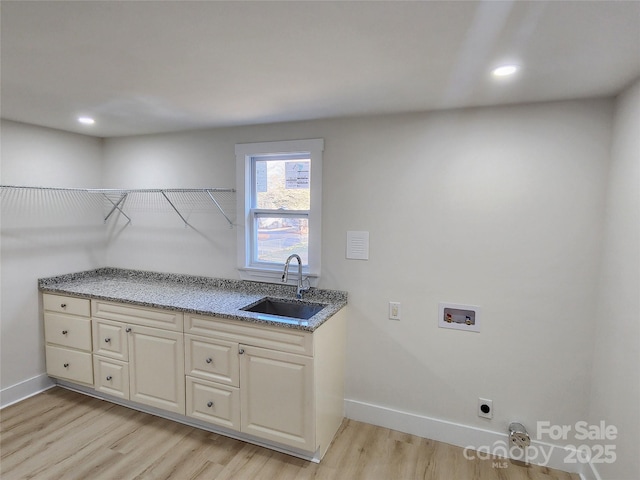 clothes washing area with baseboards, a sink, light wood-type flooring, washer hookup, and electric dryer hookup