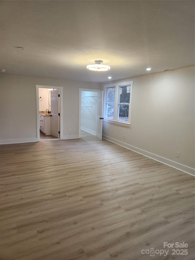 empty room featuring light wood-style floors, baseboards, and recessed lighting