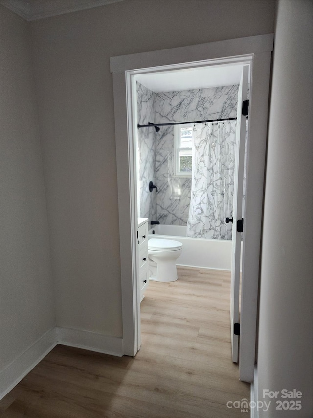 bathroom with toilet, shower / bath combo, baseboards, and wood finished floors