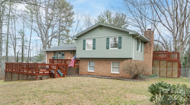 view of front of house featuring brick siding, a chimney, a front yard, and a wooden deck