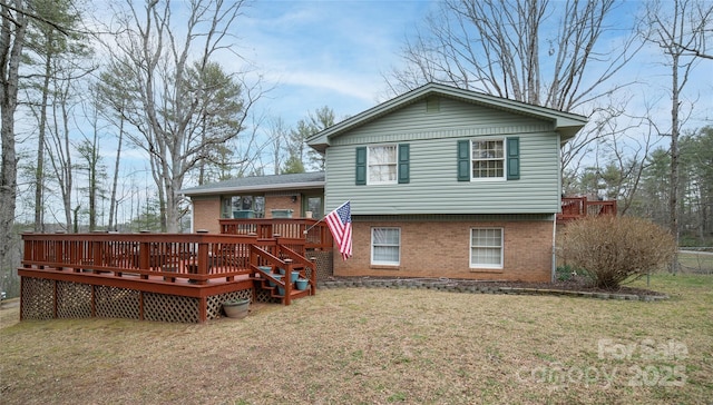 rear view of house featuring brick siding, a lawn, and a wooden deck