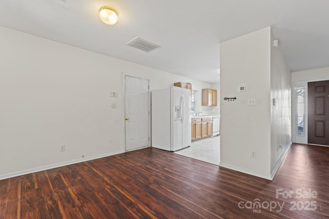 unfurnished room featuring visible vents, a sink, baseboards, and wood finished floors