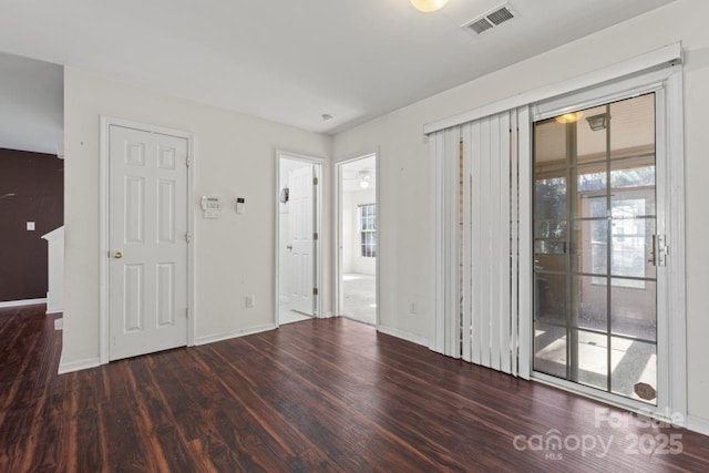 spare room with wood finished floors, visible vents, and baseboards