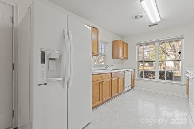 kitchen with white appliances, a sink, visible vents, light countertops, and light floors