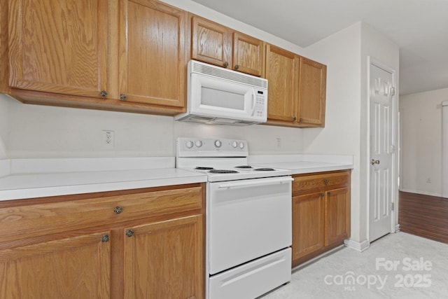 kitchen featuring white appliances, baseboards, light countertops, and brown cabinetry