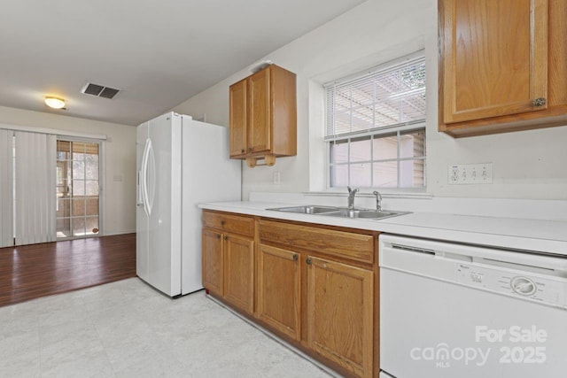 kitchen with light countertops, white appliances, a sink, and visible vents