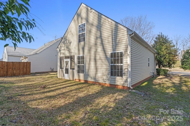 rear view of property featuring a yard and fence