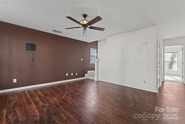 unfurnished room with a wealth of natural light, visible vents, stairway, and wood finished floors