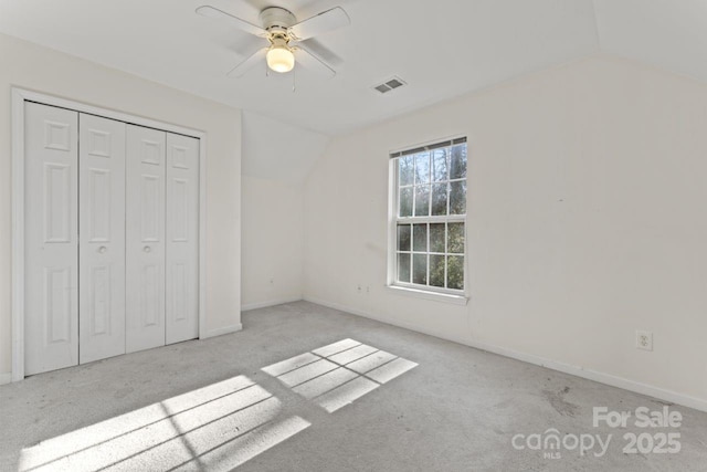 unfurnished bedroom with vaulted ceiling, carpet floors, a closet, and visible vents