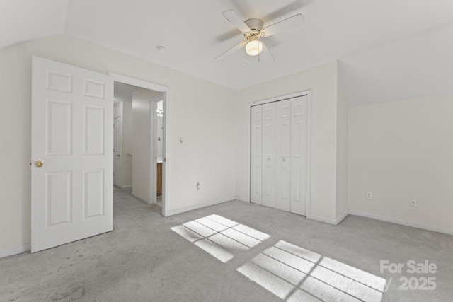 unfurnished bedroom featuring baseboards, ceiling fan, carpet, vaulted ceiling, and a closet