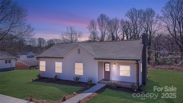 view of front of home featuring a shingled roof, a chimney, and a lawn