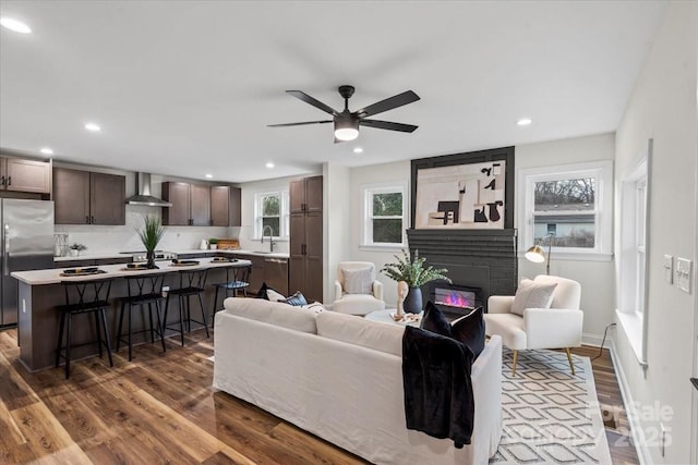 living room featuring ceiling fan, recessed lighting, a large fireplace, wood finished floors, and baseboards