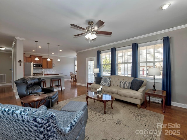 living area with a ceiling fan, visible vents, baseboards, ornamental molding, and dark wood-style floors