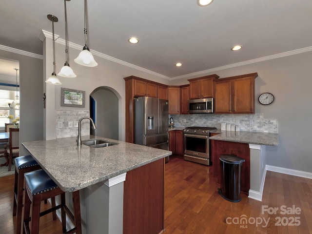 kitchen featuring arched walkways, appliances with stainless steel finishes, a peninsula, light stone countertops, and a sink