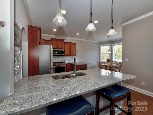 kitchen with a peninsula, a sink, ornamental molding, appliances with stainless steel finishes, and backsplash