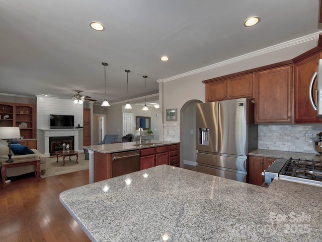 kitchen with arched walkways, a peninsula, a sink, appliances with stainless steel finishes, and crown molding