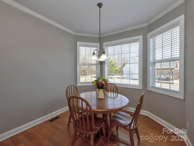 dining space featuring a notable chandelier, wood finished floors, visible vents, and baseboards