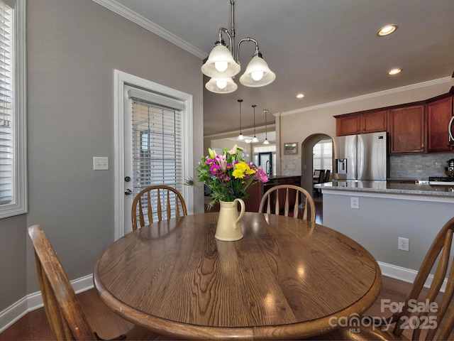 dining room with arched walkways, dark wood-style flooring, baseboards, and crown molding