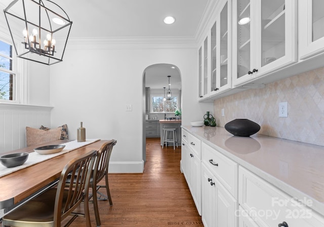 interior space with dark wood-type flooring, light countertops, crown molding, and backsplash