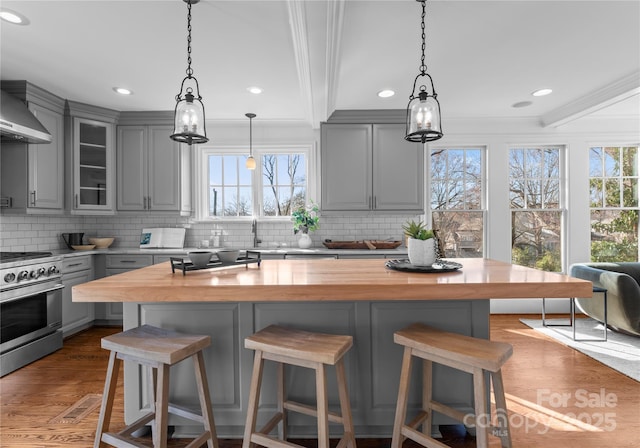 kitchen with wood counters, stainless steel range with electric cooktop, gray cabinets, glass insert cabinets, and crown molding