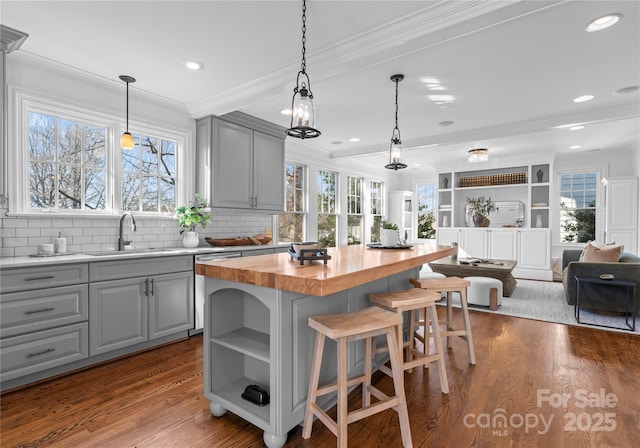 kitchen with butcher block countertops, gray cabinets, a sink, and ornamental molding