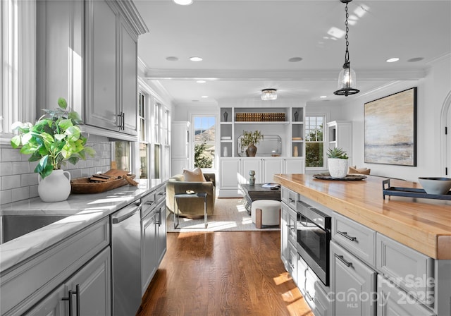 kitchen with dark wood finished floors, stainless steel appliances, wooden counters, gray cabinetry, and ornamental molding