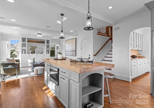 kitchen with dark wood-style floors, open shelves, butcher block counters, hanging light fixtures, and ornamental molding