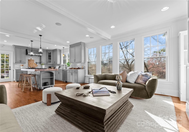 living area featuring light wood-type flooring, recessed lighting, crown molding, and beamed ceiling