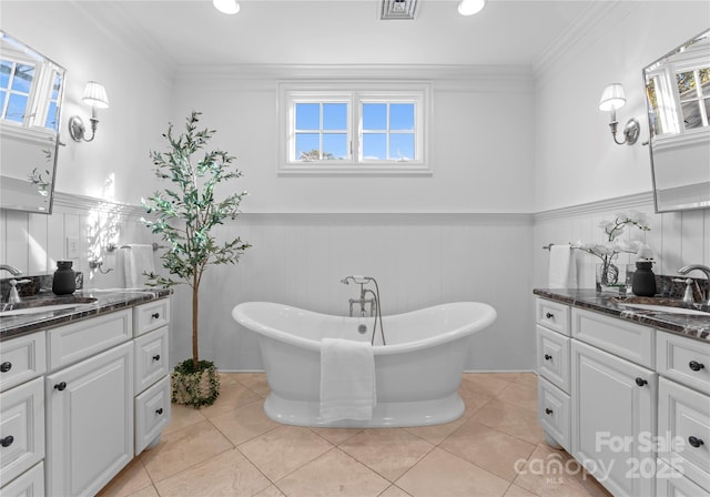 full bath with a soaking tub, wainscoting, a sink, and crown molding