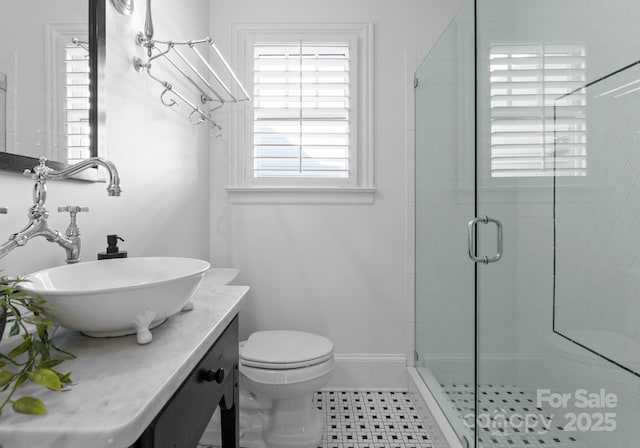 bathroom featuring toilet, a stall shower, vanity, and baseboards